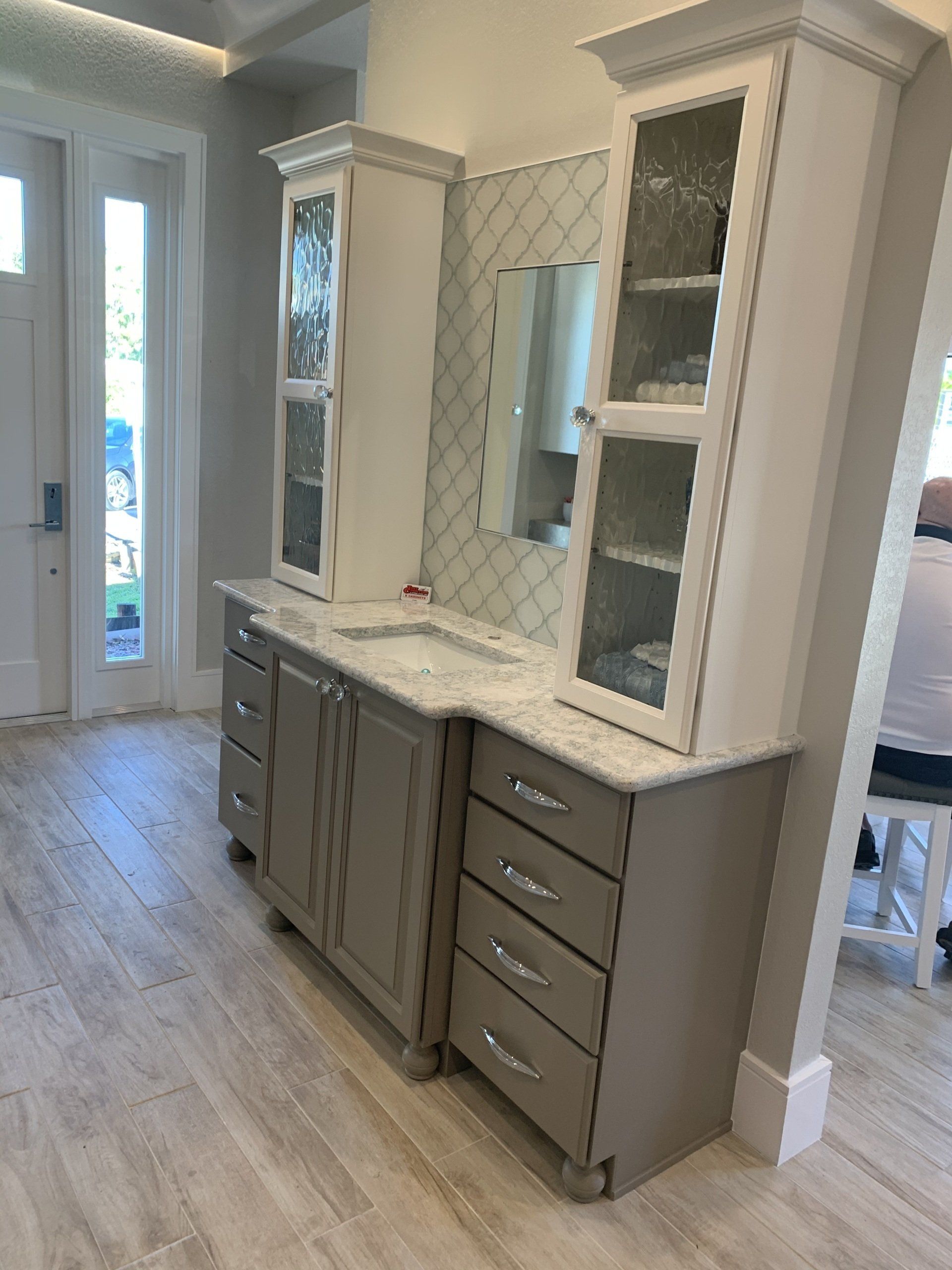 JCAOS showroom vanity display with glass door tower cabinets and Cambria Montgomery quartz countertops.