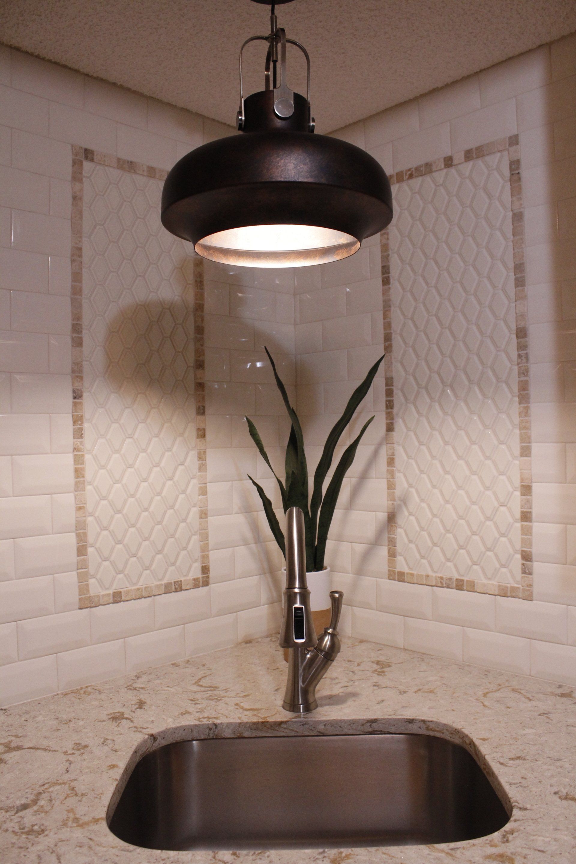 Rustic metal light fixture surrounded by white subway tile with detailed inlay