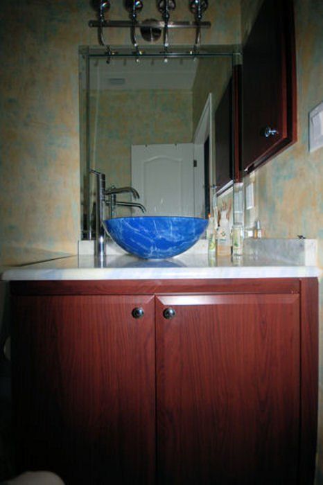 Blue marbled vessel sink above new dark stained slab door vanity for bathroom remodel.