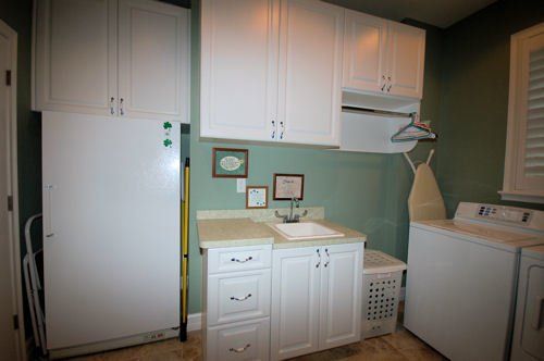 Clean white cabinetry in laundry room with solid surface countertops.