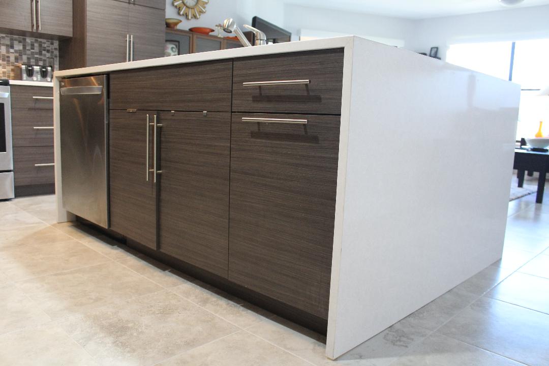 Horizontal grained slab doors and drawers on island with quartz waterfall ends and large euro pulls.