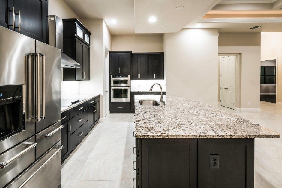 Black kitchen with large island. Stainless steel appliances and quartz countertops.