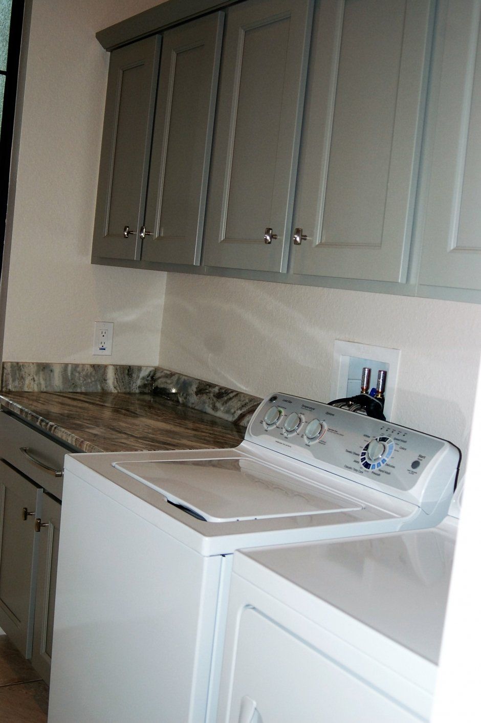 Grey painted face frame upper cabinets with polished nickel knobs and crown molding.