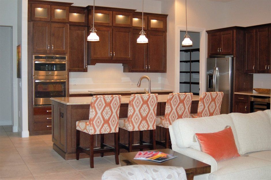 Warm stained shaker kitchen with stacked illuminated uppers with glass doors. Open concept remodel.