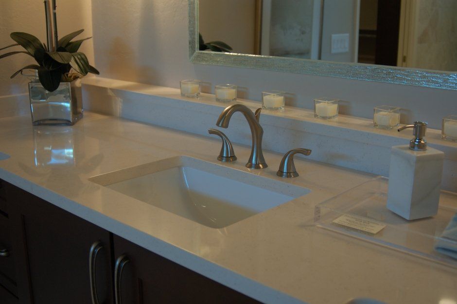 White quartz countertop with rectangle porcelain sink and matching quartz ledge above backsplash. Bathroom remodel.