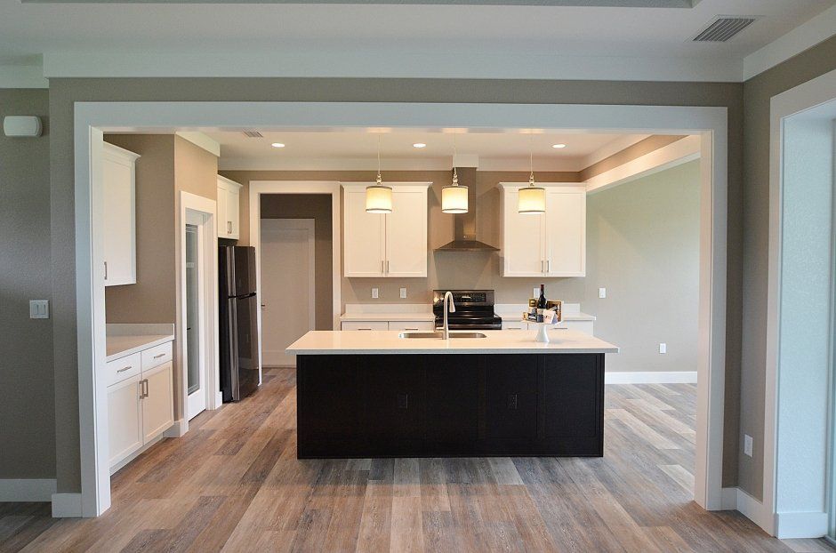 Contrasting black island cabinetry surrounded by white shaker perimeter cabinets.