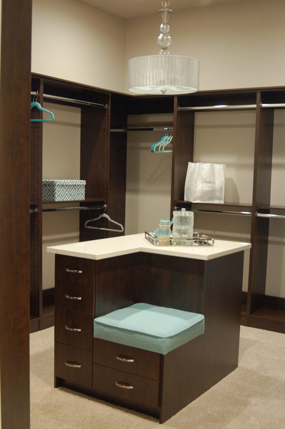 Dark wood grain closet cabinetry with elegant light fixture. Adjustable chrome closet rods.