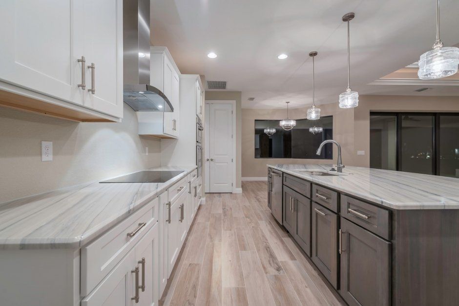 Elegant pendant lights above dark stained accent island with marbled white quartz countertops.