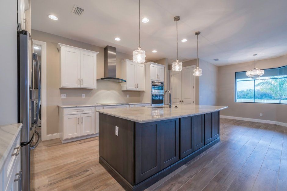 Clean and bright new construction kitchen with white shaker cabinetry and dark stained island. Storage cabinets on island.