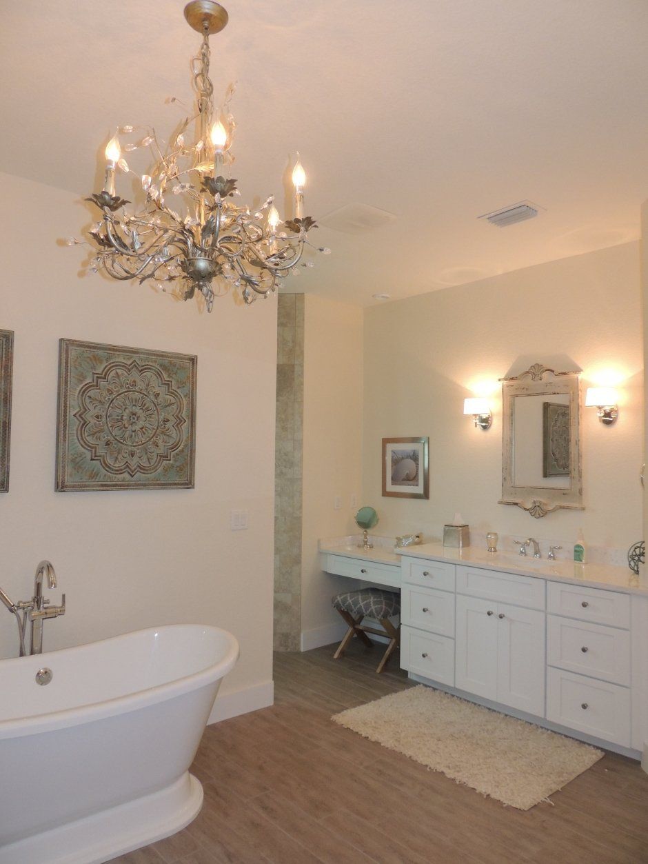 Breathtaking chandelier in master bathroom remodel with tasteful wall decor and makeup area.