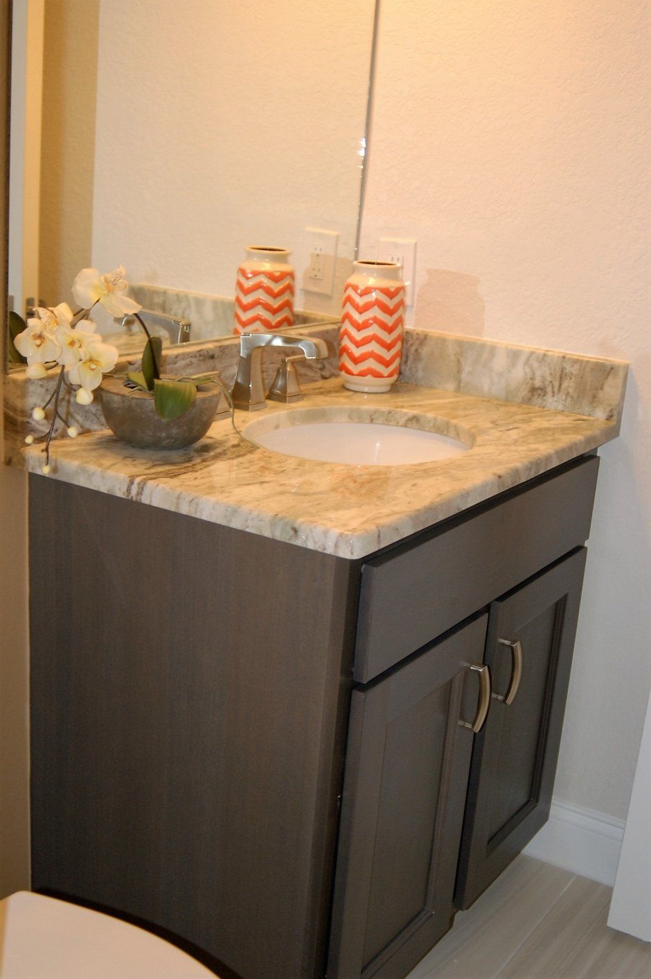 Dark quartz countertop on guest bathroom vanity remodel project. Brown stained wood cabinetry.