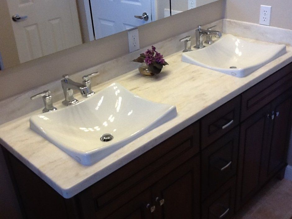 Unique drop-in porcelain lavatory sinks in stone countertop with dark brown stained cabinetry.
