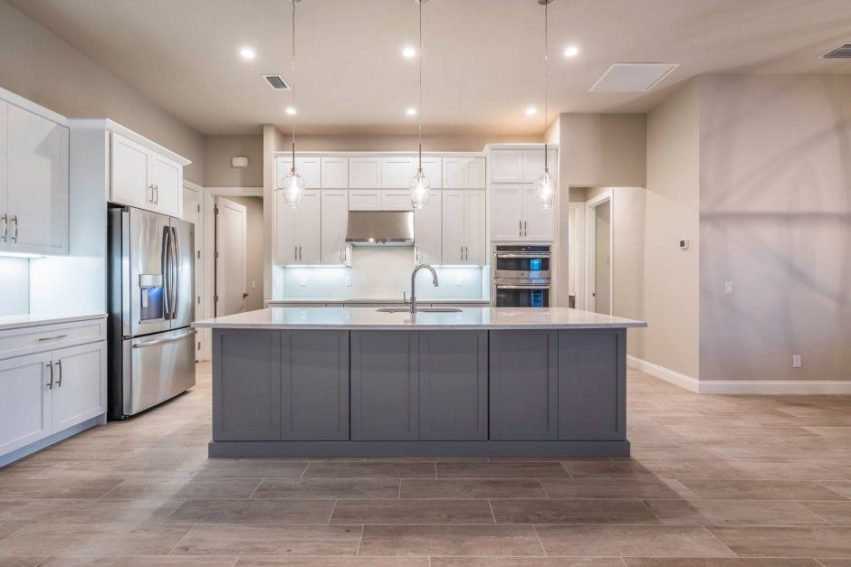 Large white painted shaker kitchen with accent grey island. White quartz countertops.