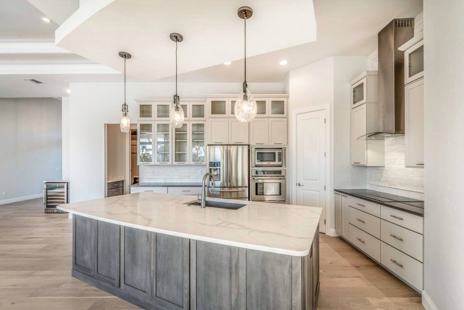 Large accent island with quartz countertops. Sleek cooktop with decorative stainless hood.