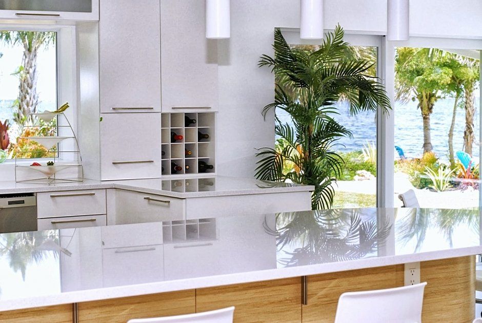 Modern white kitchen with slab doors and drawers. White quartz countertops with a view of the water.