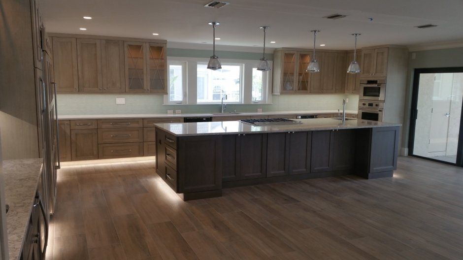 Large natural colored kitchen with ample lighting and accented dark island cabinetry.