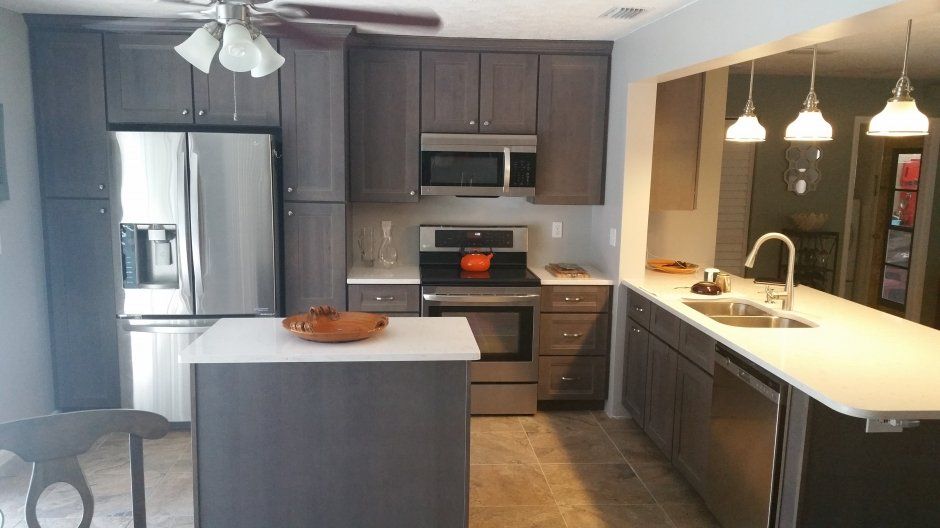 Dark stained shaker cabinetry with stainless appliances. Small island in the center.