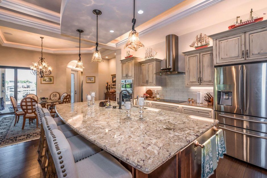 Rustic weathered grey cabinetry with under cabinet lighting. Large stone island countertop.