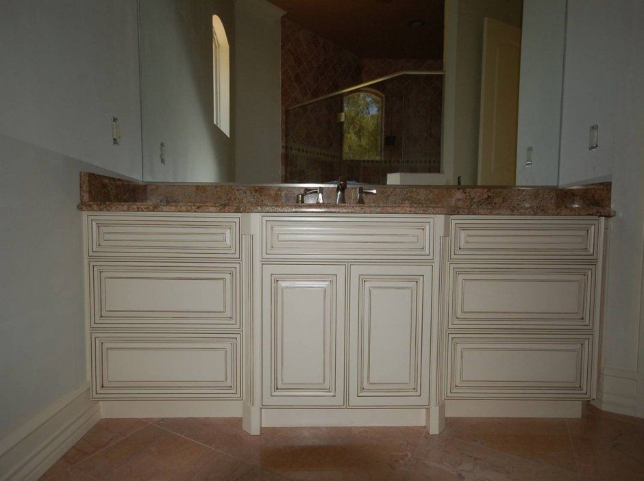 Ornate raised panel off-white vanity cabinets with brown pencil glaze. Bath remodel.