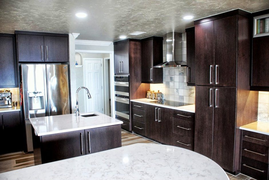 Bright white quartz countertops on dark stained wood cabinets. Double wall oven.