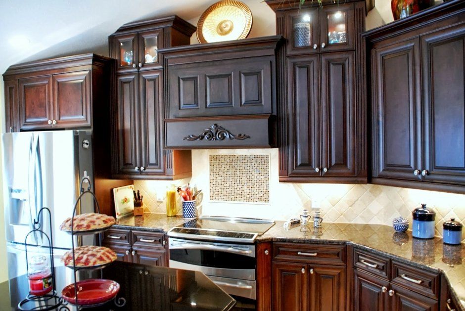 Dark stained raised panel cabinetry in kitchen remodel. Accent backsplash above slide-in range.