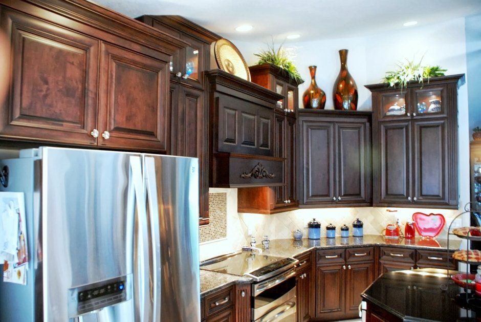 Cozy raised panel kitchen remodel with decorative wood hood and stacked upper cabinets.