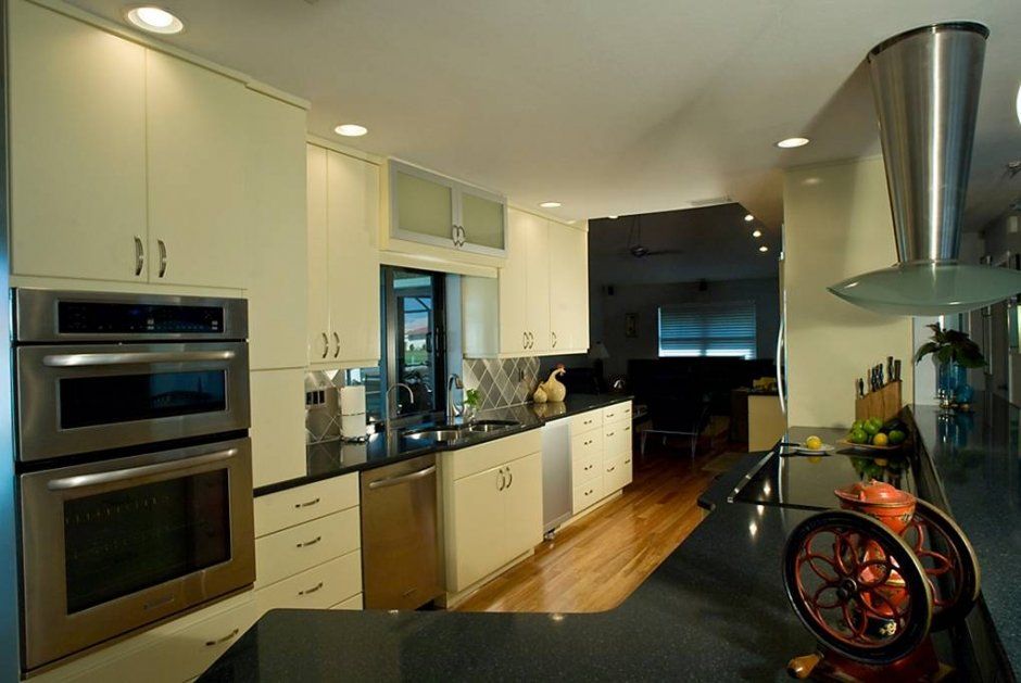 Slab doors and drawers in white kitchen with dark black stone countertops and stainless appliances.
