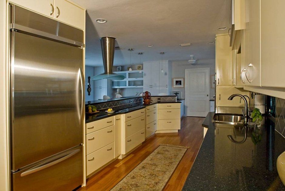 Large pot and pan drawers in white kitchen with black stone countertops. Recessed lighting in ceiling.