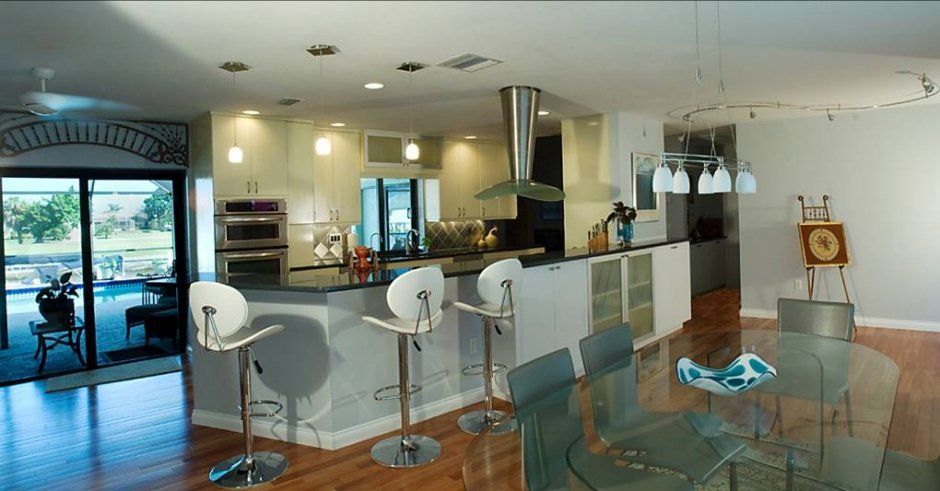 Unique decorative hood above cooktop. Storage cabinets next to level bar seating area.