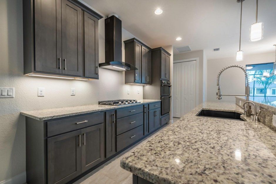 Dark stained wood cabinetry with under cabinet lighting. Gas cooktop with decorative hood.