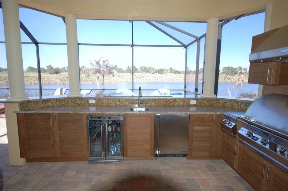 Floridian outdoor kitchen with beverage center, grill, and a waterfront view. Stainless appliances