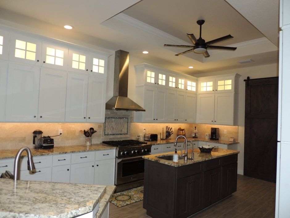 Glass doors with mullions in stacked upper cabinetry with interior lighting. Shaker style