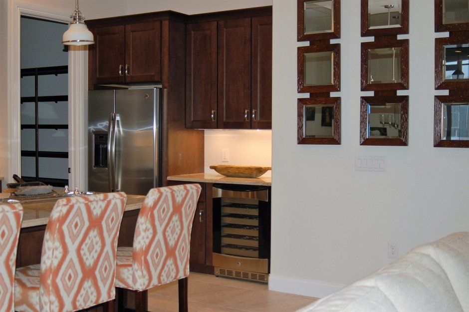 Under counter wine refrigerator in traditional dark stained shaker kitchen remodel.