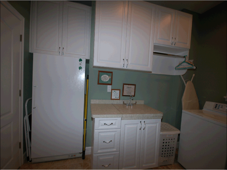 Clean white cabinetry in laundry room with solid surface countertops.