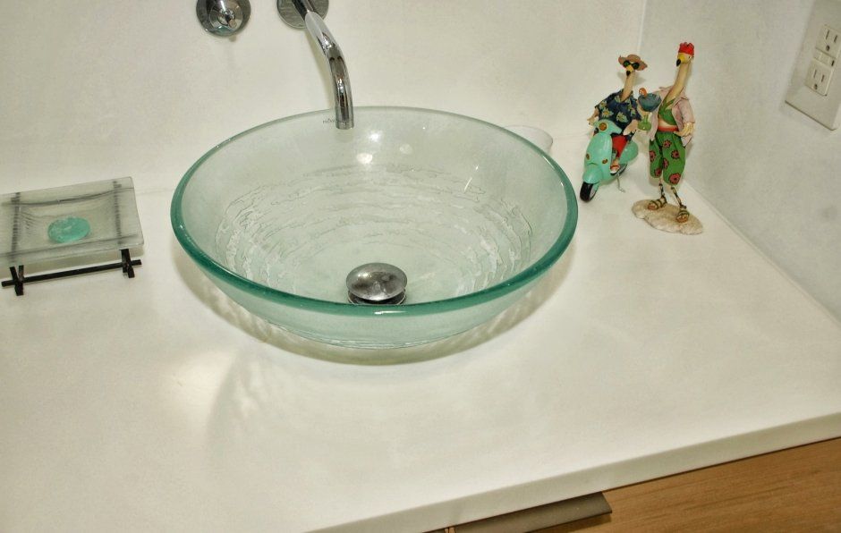 Clear glass vessel sink bowl with wall mounted faucet in bathroom remodeling project.