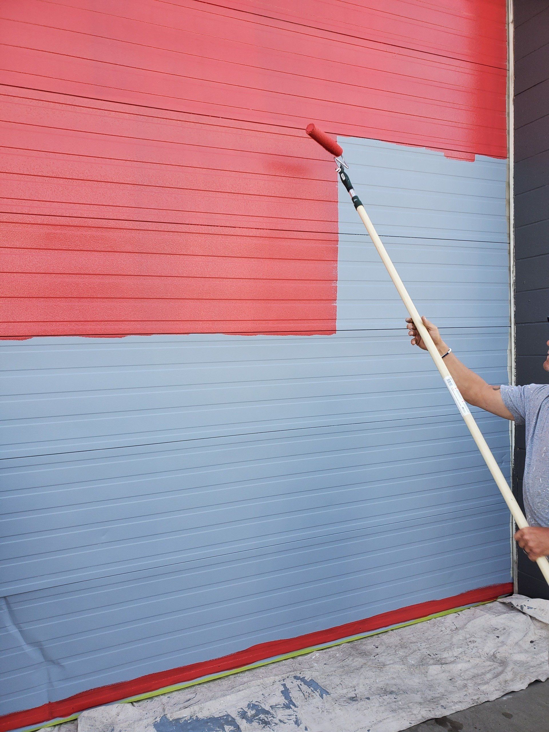Peninsula painting a red and blue wall with a roller