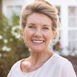 Oral Appliance Therapy to Treat Obstructive Sleep Apnea — Woman Smiling While Sitting in Dental Chair in Burlington, IA