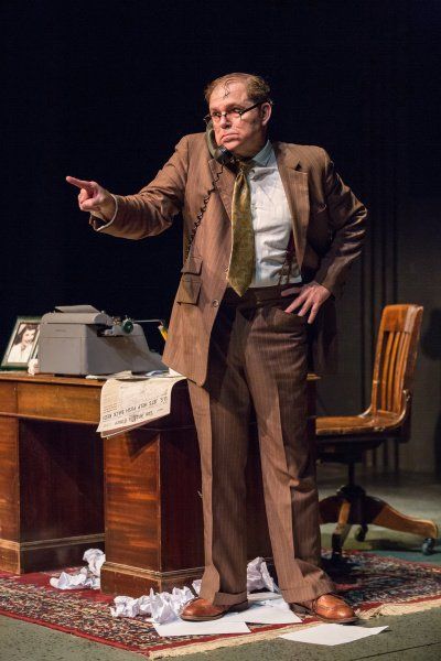 Bernie standing next to his desk talking on phone making a point.