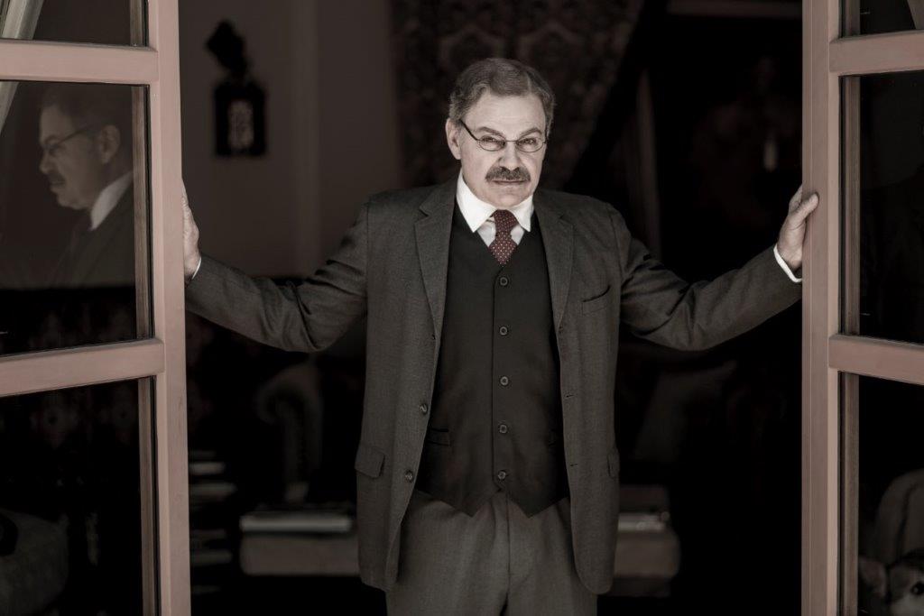 Actor Phil Johnson as President T. Roosevelt standing in doorway with arms raised at  his sides