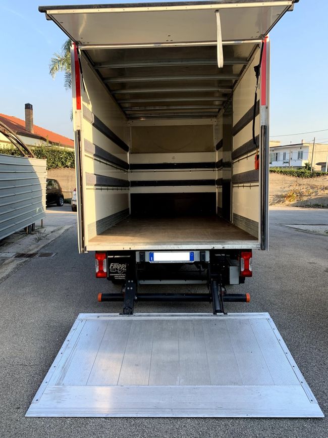 Camion per consegne a cielo aperto con rampa posteriore in alluminio abbassata, parcheggiato all'aperto.