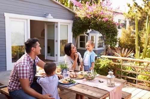 Family At Home Eating Outdoor Meal In Garden Together — Basement & Crawlspace Waterproofing in Scotch Plains, NJ Family At Home Eating Outdoor Meal In Garden Together — Basement & Crawlspace Waterproofing in Scotch Plains, NJ