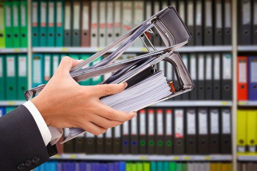 due mani che afferrando due raccoglitori e dietro una libreria con tanti raccoglitori