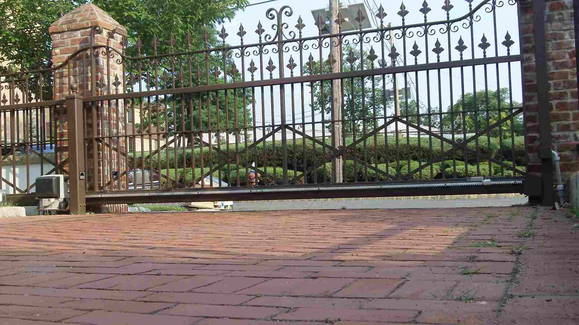 Iron gate and brick walkway in front of a landscaped garden or historic building