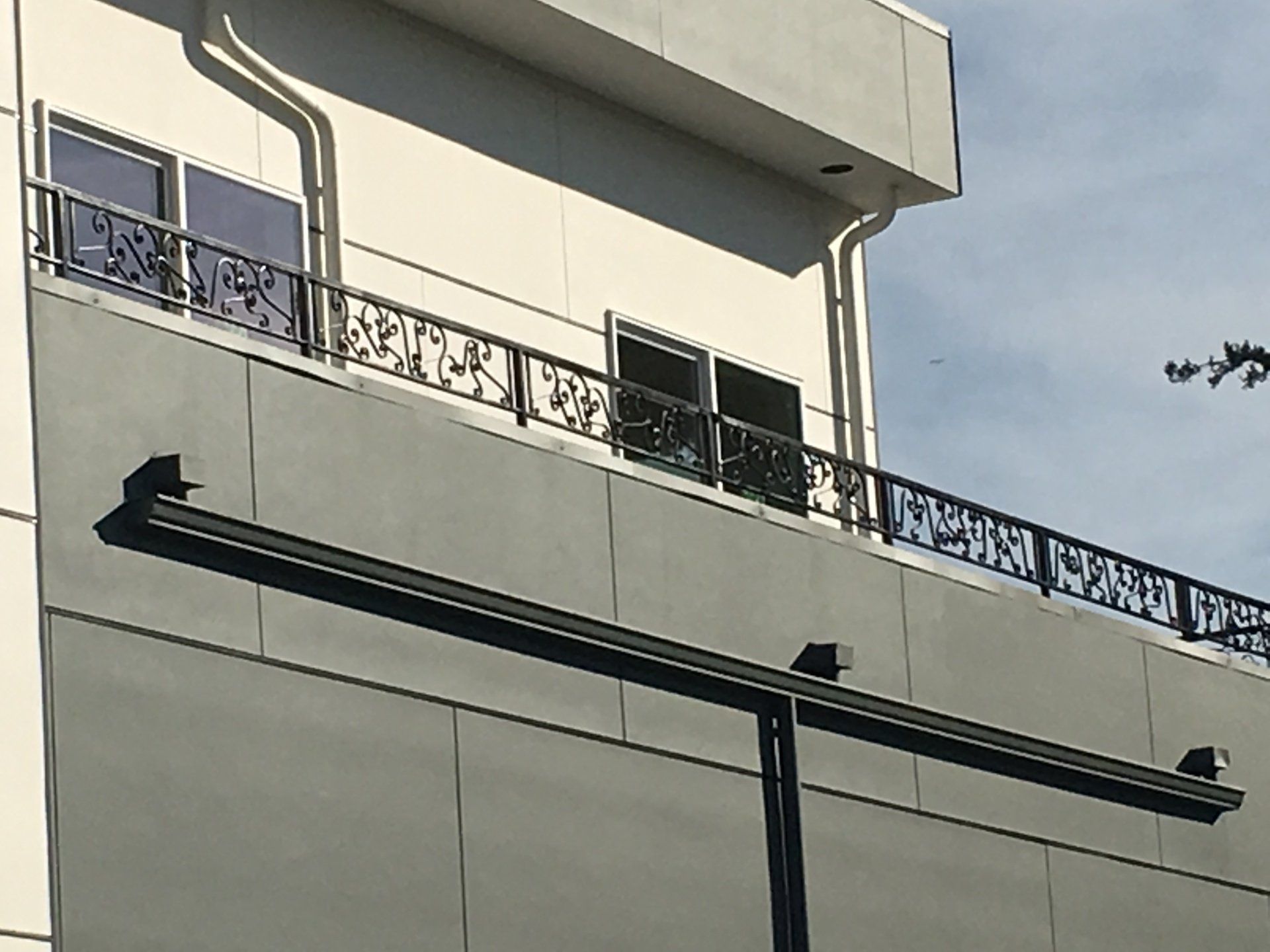 Modern building facade with balconies, decorative railing, and wall-mounted light fixtures