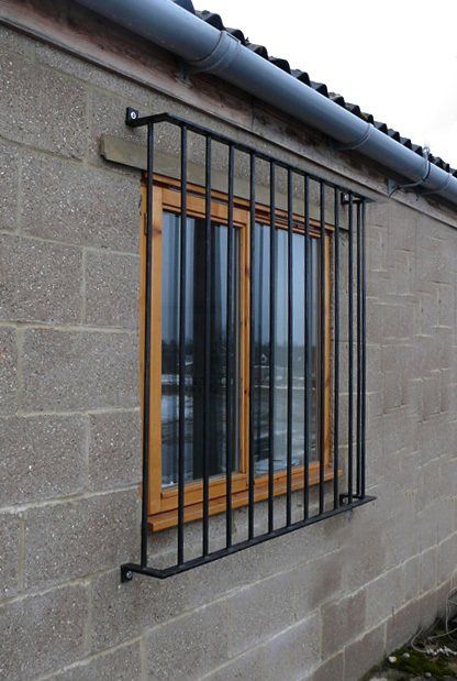 Window with black security bars on a gray cinder block wall of a house