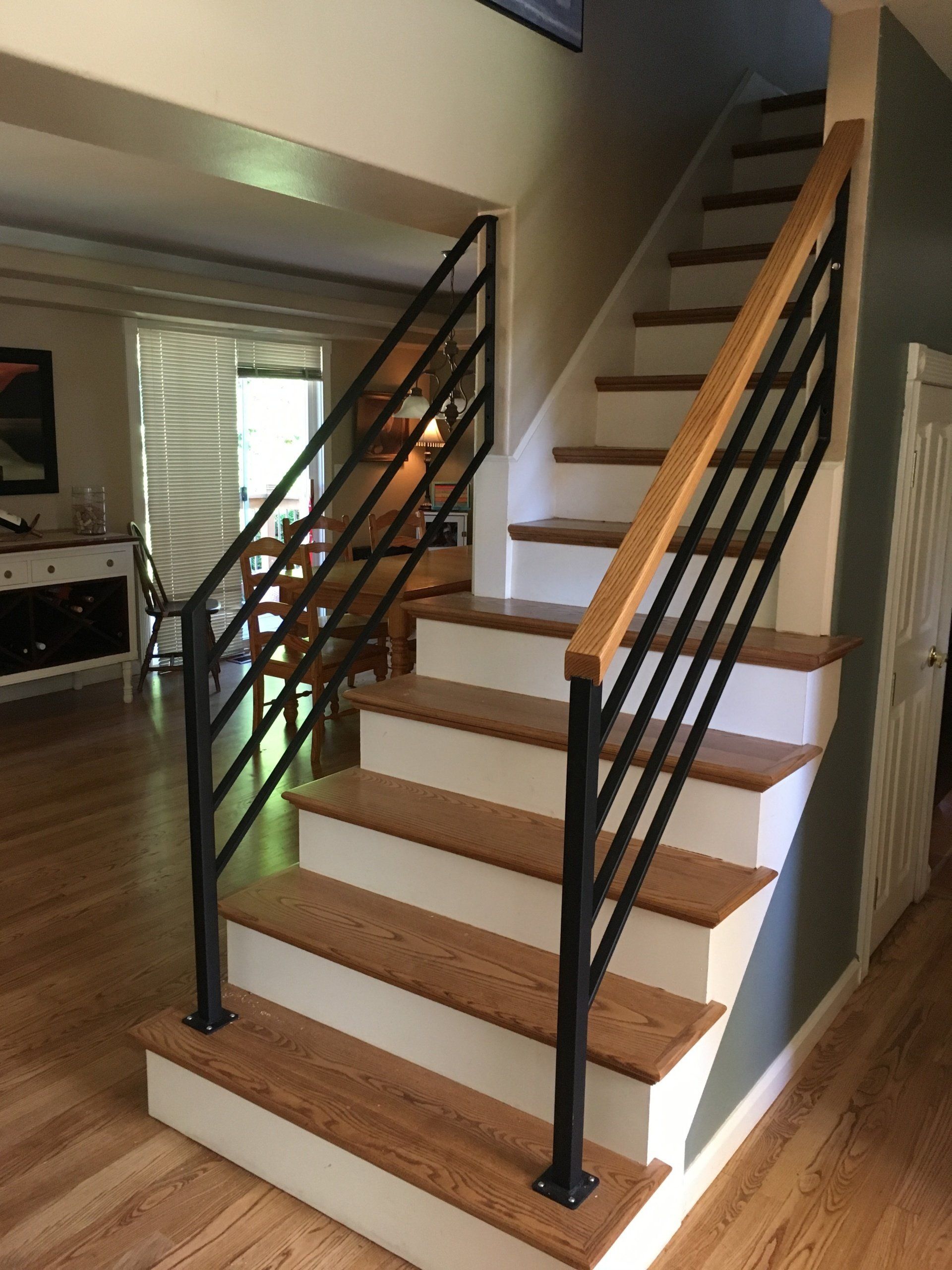 Indoor staircase with dark railings, white steps, and wood treads in a bright home interior