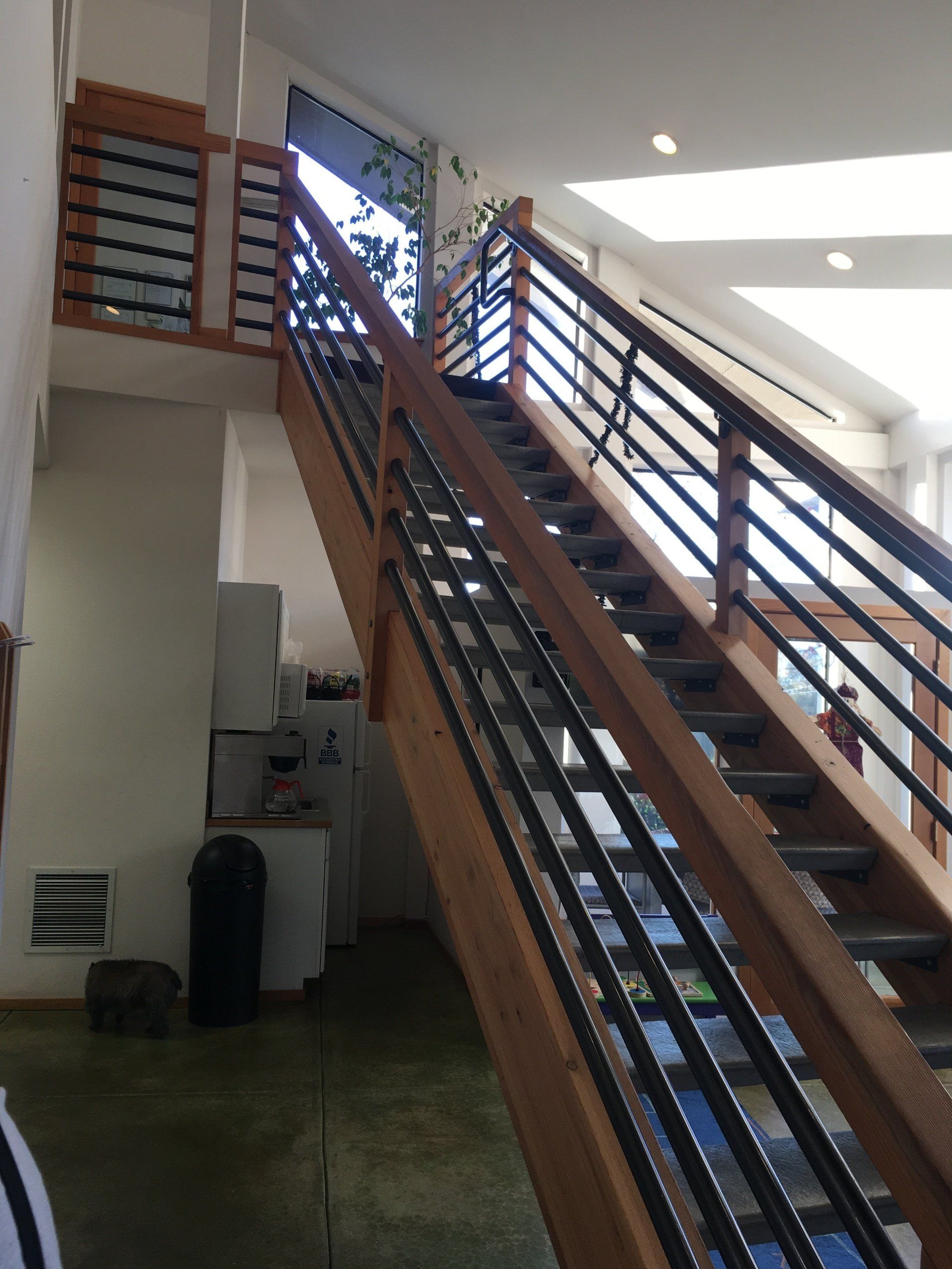 Indoor stairwell with long metal-railed stairs and a bright skylight above