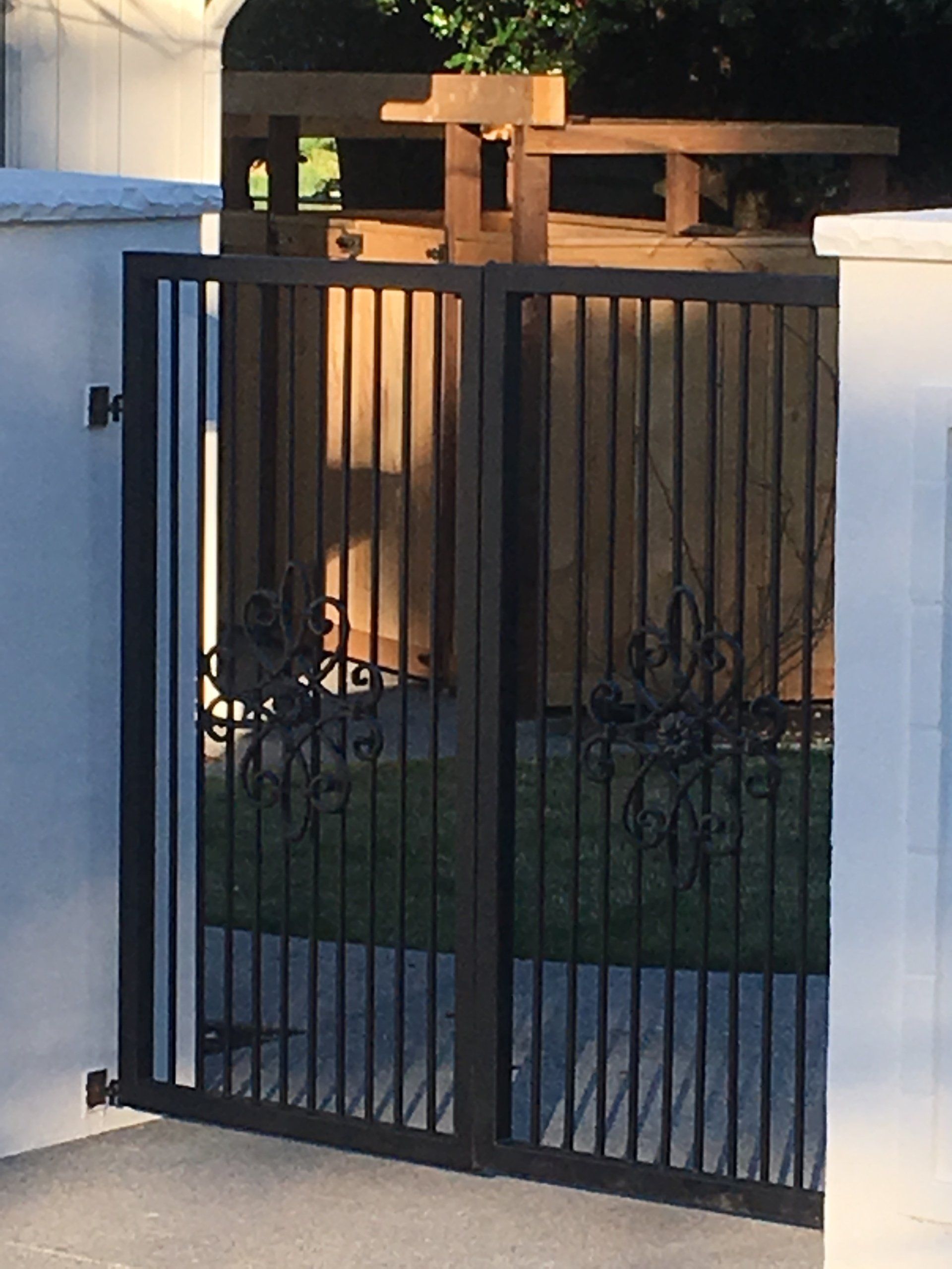 Black metal gate in front of a wooden fence and yard at dusk