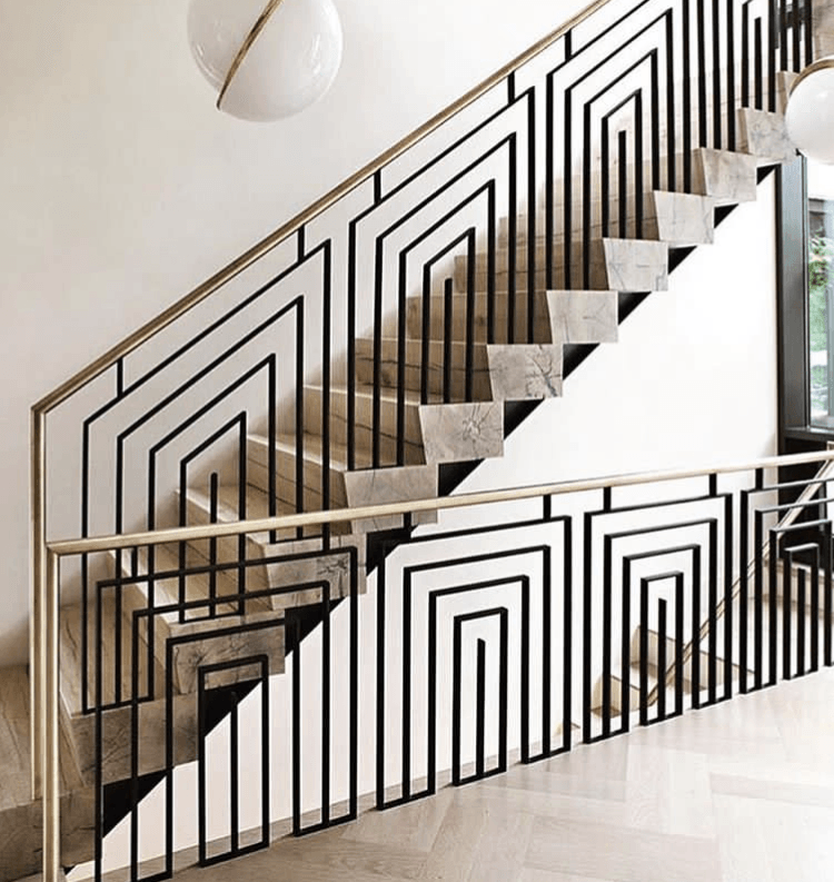 Modern indoor staircase with black geometric railings and beige steps in a bright white interior