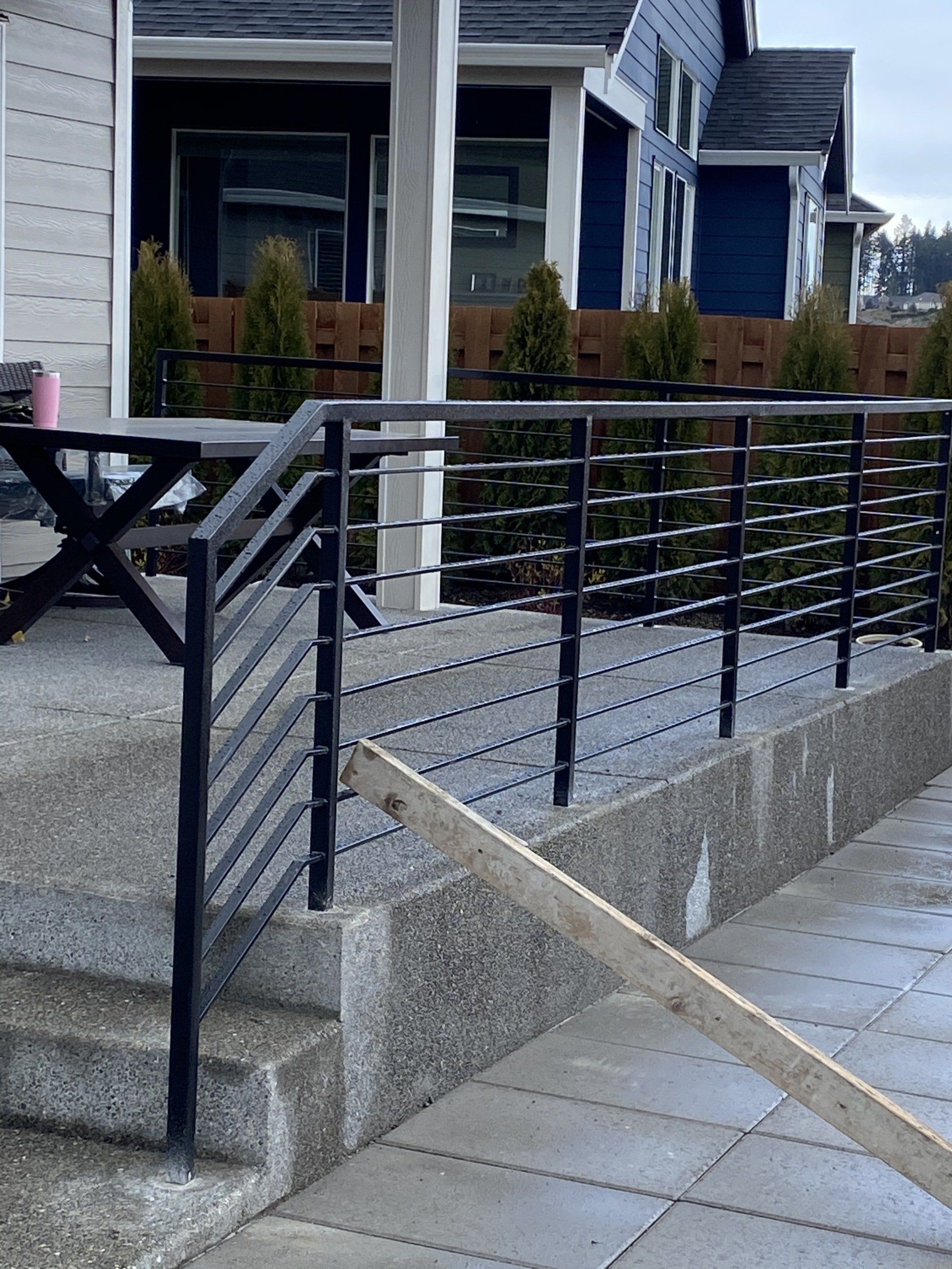 Accessible ramp with black metal railings beside a house entrance and stairs